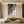 Hand-painted 3D textured abstract wall art featuring undulating waves in terracotta and beige, styled in a modern Boho living room above a beige sofa.