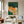 Handmade modernist oil painting showing an anthropomorphic orange tiger sleeping peacefully in a dark green bed, resting on a yellow pillow, and tucked under a striped green and white blanket.