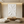 A close-up of a hand-painted all-white 3D textured oil painting featuring thick, expressive impasto strokes and sculptural ridges, styled in a bright, modern minimalist living room.