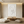 A hand-painted 3D textured oil painting in pure white featuring bold, horizontal wave-like ridges with heavy impasto relief, displayed in a bright modern minimalist room.